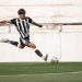 Dynamic shot of a soccer player in mid-air kick on green field.